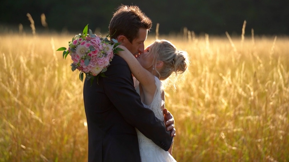 Couple de mariés dans un champ au coucher du soleil